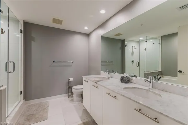 Full bath featuring double vanity, a stall shower, recessed lighting, and light tile patterned flooring
