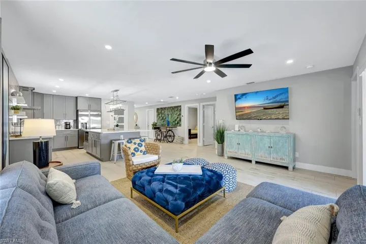 Living room featuring ceiling fan, light wood-type flooring, and a chandelier