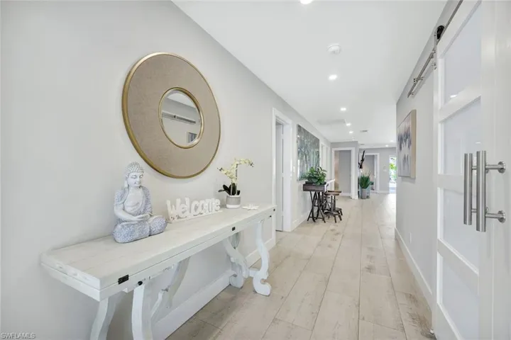 Corridor featuring a barn door, light wood-style flooring, and recessed lighting