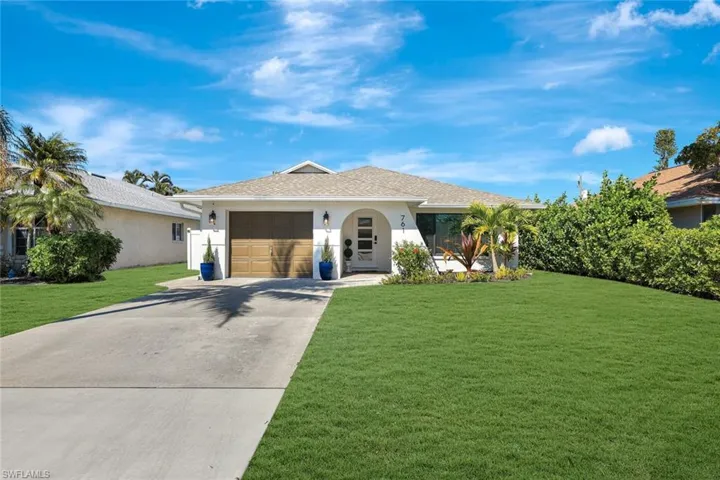 Ranch-style house with a front yard, concrete driveway, stucco siding, and a garage