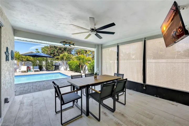 Outdoor pool with outdoor dining space, a grill, a patio area, and a sunroom