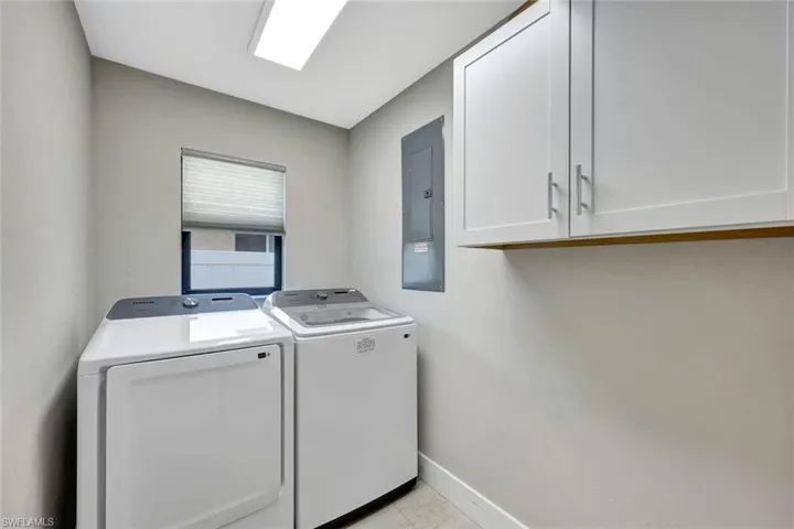 Laundry area with cabinet space, electric panel, and washer and clothes dryer
