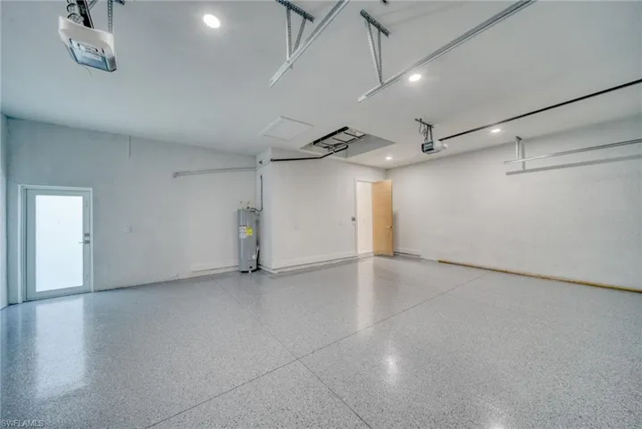 Garage featuring electric water heater, a garage door opener, and recessed lighting