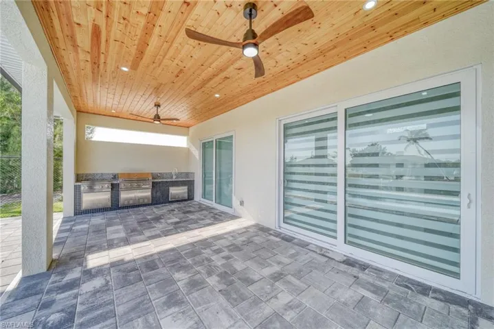 View of patio featuring exterior kitchen, a ceiling fan, fence, and a grill