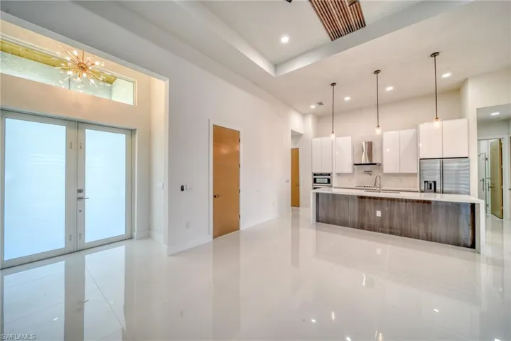 Kitchen featuring appliances with stainless steel finishes, modern cabinets, wall chimney exhaust hood, a sink, and white cabinets