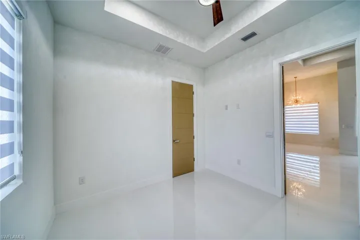 Tiled empty room with a chandelier and baseboards