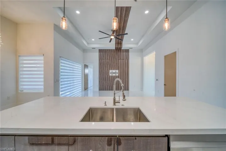 Kitchen featuring a sink, a center island with sink, open floor plan, light stone counters, and recessed lighting