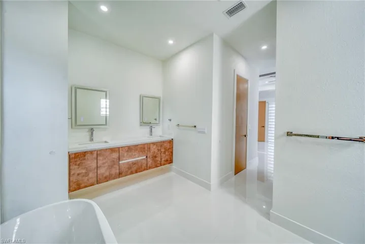 Bathroom with a freestanding tub, double vanity, recessed lighting, and tile patterned flooring