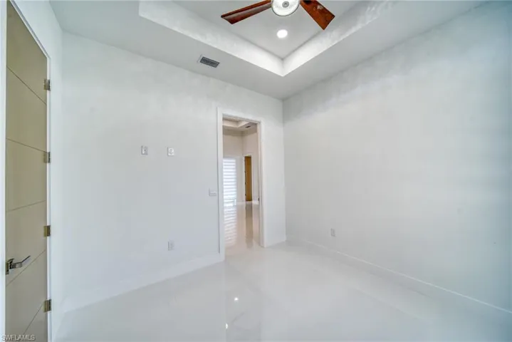 Empty room featuring a ceiling fan, a raised ceiling, baseboards, and light tile patterned flooring