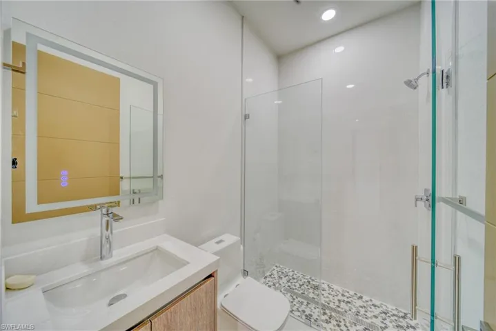 Bathroom featuring tiled shower, toilet, and vanity