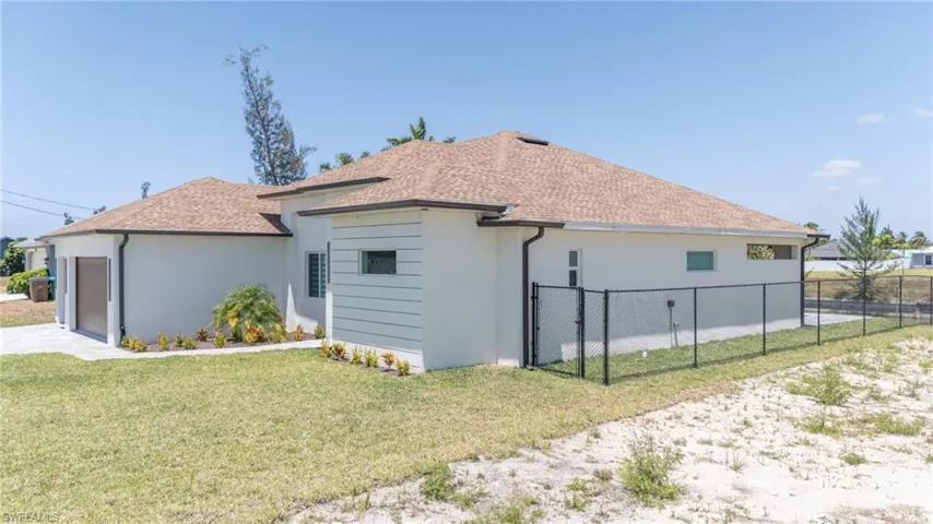 View of side of property with stucco siding, roof with shingles, an attached garage, and a gate