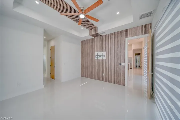 Tiled empty room featuring a raised ceiling, recessed lighting, ceiling fan, and wallpapered walls