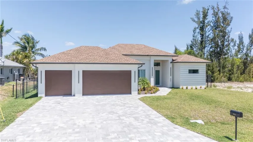 View of front facade featuring a garage, stucco siding, decorative driveway, and central AC