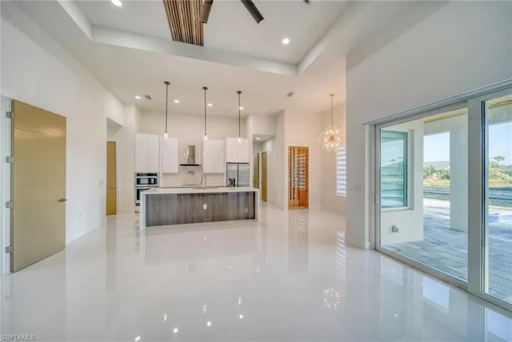 Kitchen with modern cabinets, wall chimney exhaust hood, white cabinets, a high ceiling, and stainless steel appliances