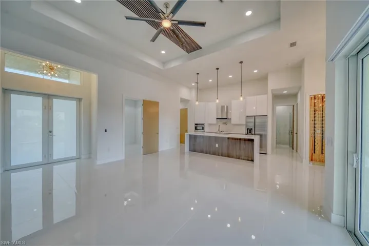 Unfurnished living room featuring a raised ceiling, recessed lighting, light tile patterned floors, french doors, and a high ceiling