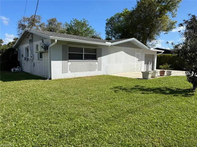 View of side of home with a lawn, stucco siding, and a patio area