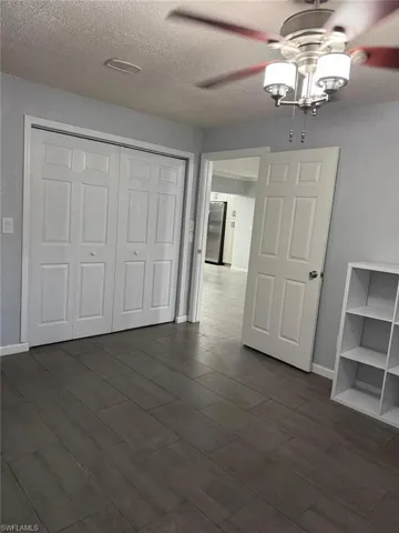 Bedroom ceiling fan, a textured ceiling, and dark wood-style flooring