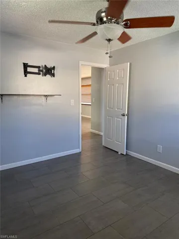 Empty room with a ceiling fan and a textured ceiling