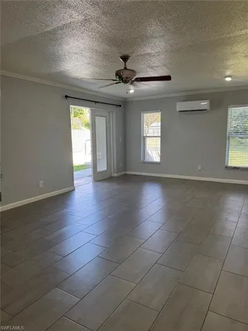 Unfurnished room featuring crown molding, ceiling fan, healthy amount of natural light, and a textured ceiling