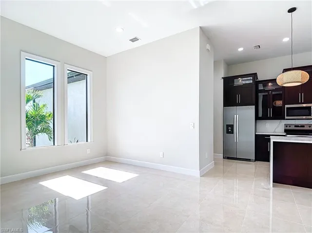 Kitchen with decorative light fixtures, light tile floors, a wealth of natural light, and appliances with stainless steel finishes
