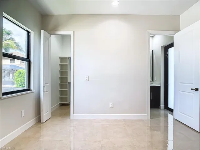 Unfurnished bedroom featuring a spacious closet and light tile flooring