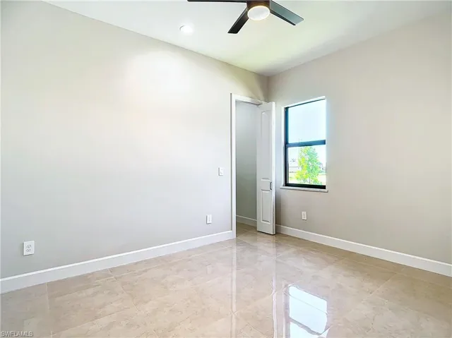 Empty room featuring ceiling fan and light tile flooring