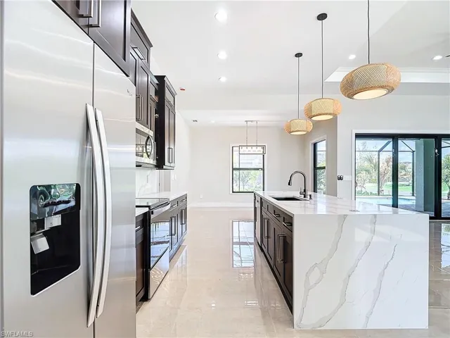 Kitchen with pendant lighting, stainless steel appliances, a kitchen island with sink, and sink