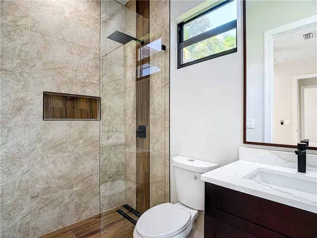 Bathroom featuring an enclosed shower, toilet, and vanity