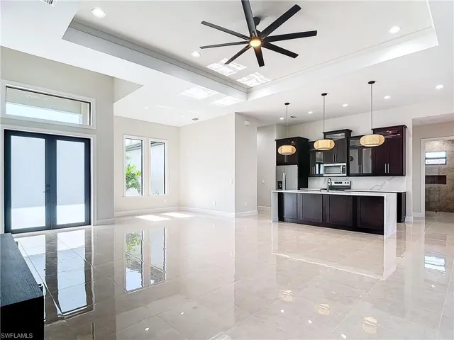 Kitchen with decorative light fixtures, a center island with sink, a wealth of natural light, and appliances with stainless steel finishes