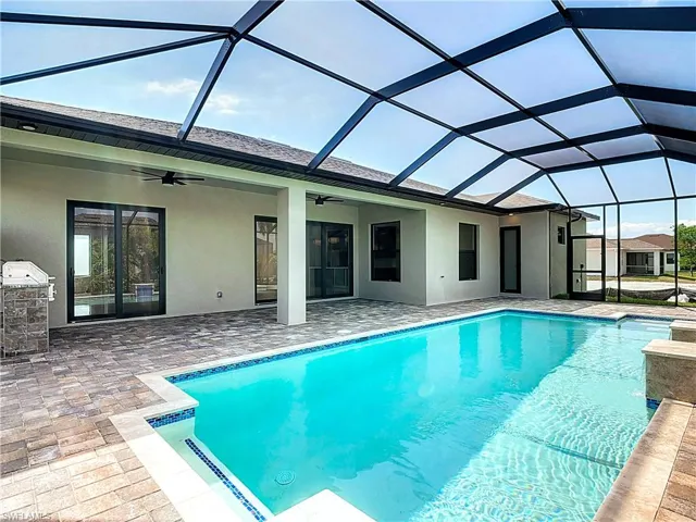 View of swimming pool featuring a patio, glass enclosure, and ceiling fan
