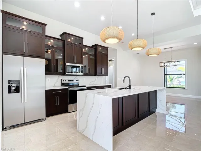 Kitchen featuring dark brown cabinetry, stainless steel appliances, a center island with sink, tasteful backsplash, and sink