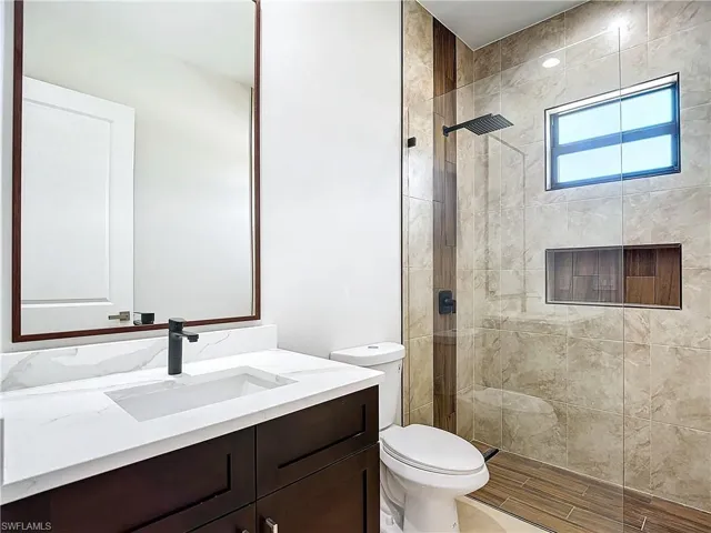 Bathroom with a shower with door, vanity, and toilet