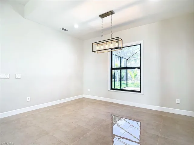 Empty room with a chandelier and light tile floors