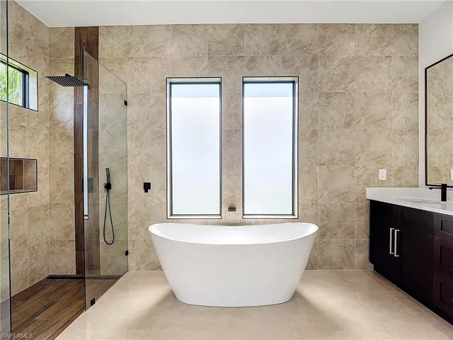 Bathroom featuring tile walls, plus walk in shower, and vanity