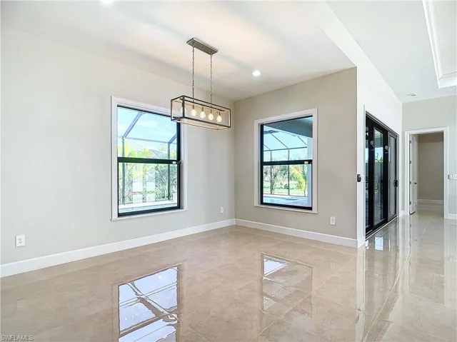 Tiled spare room with plenty of natural light and a chandelier