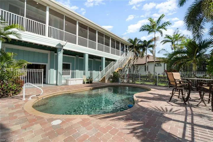 View of pool with stairs, a sunroom, fence, and a patio area