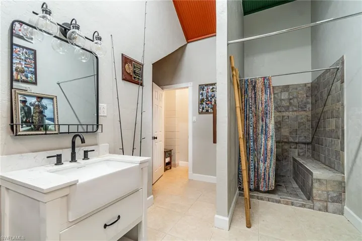 Bathroom with tile patterned flooring, vanity, baseboards, and tiled shower
