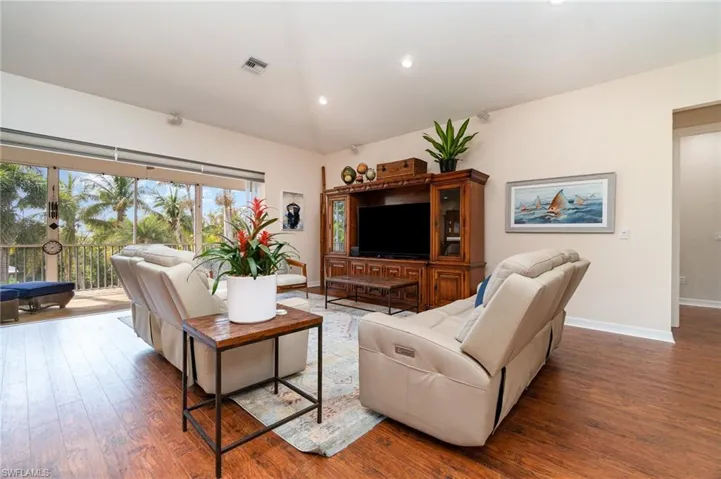 Living area with wood finished floors, baseboards, lofted ceiling, and visible vents
