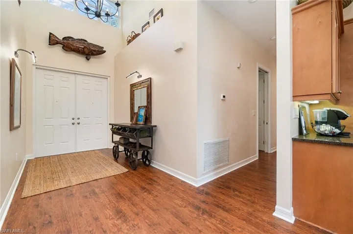 Entrance foyer featuring dark wood-style floors, baseboards, visible vents, a towering ceiling, and an inviting chandelier