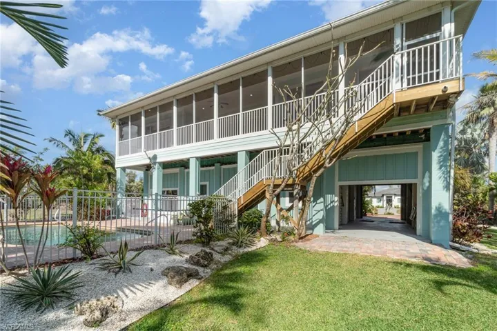 Rear view of house featuring a sunroom, fence, stairs, a yard, and a patio area