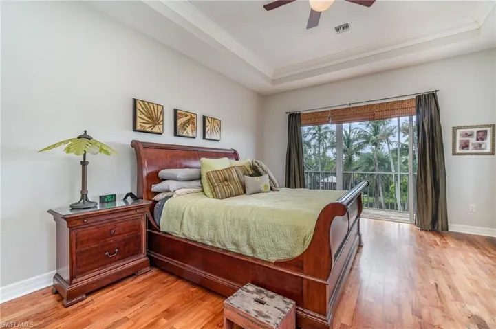 Bedroom featuring visible vents, light wood finished floors, ornamental molding, access to outside, and a raised ceiling