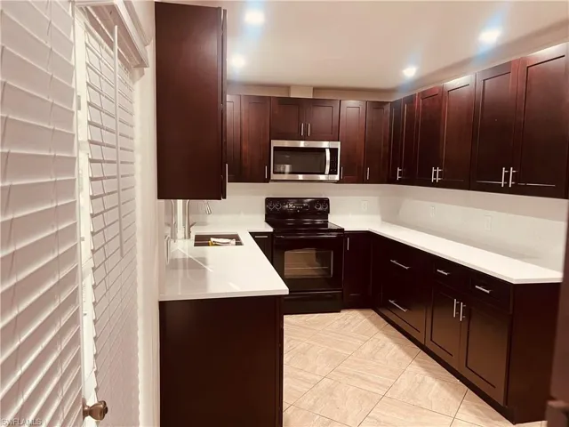 Kitchen featuring dark brown cabinets, black electric range, and sink