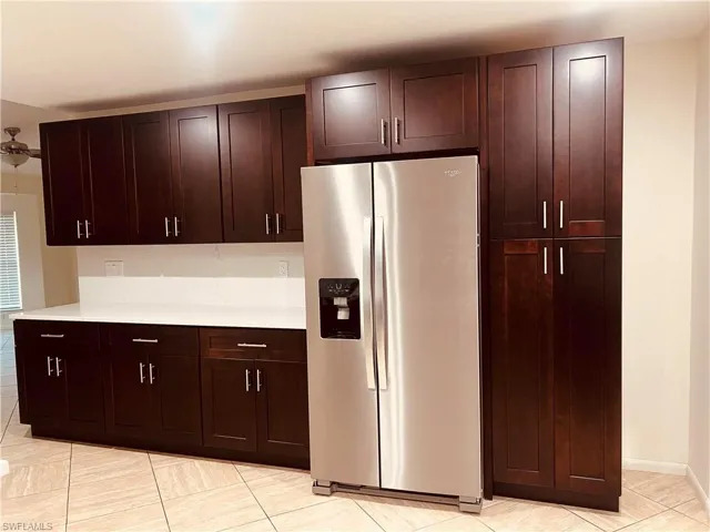 Kitchen with stainless steel fridge with ice dispenser and dark brown cabinets