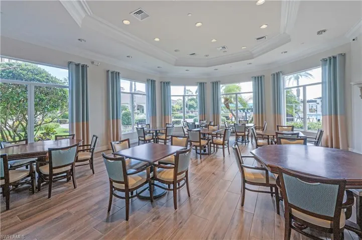 Dining space with light wood-style floors, crown molding, and a tray ceiling