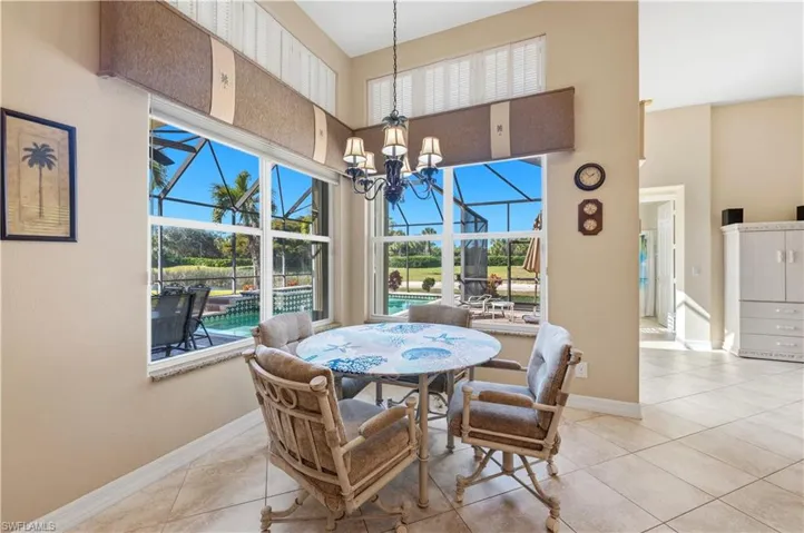 Tiled dining area featuring a sunroom, suspended lighting, and a high ceiling