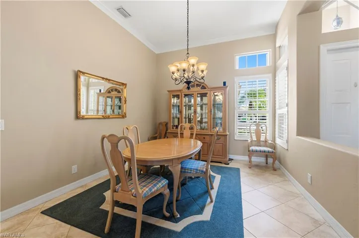 Dining area with a chandelier, light tile patterned floors, and crown molding