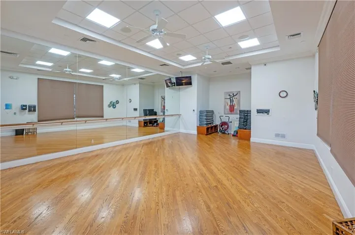 Exercise area with a drop ceiling, a tray ceiling, crown molding, and ceiling fan