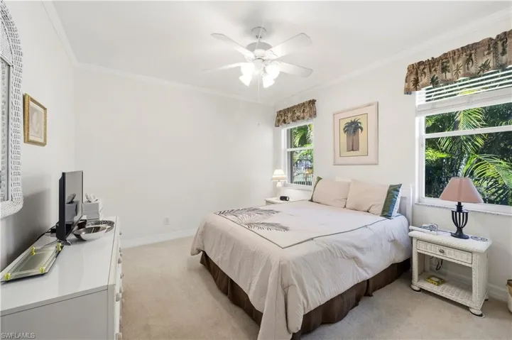 Bedroom with light carpet, crown molding, and a ceiling fan