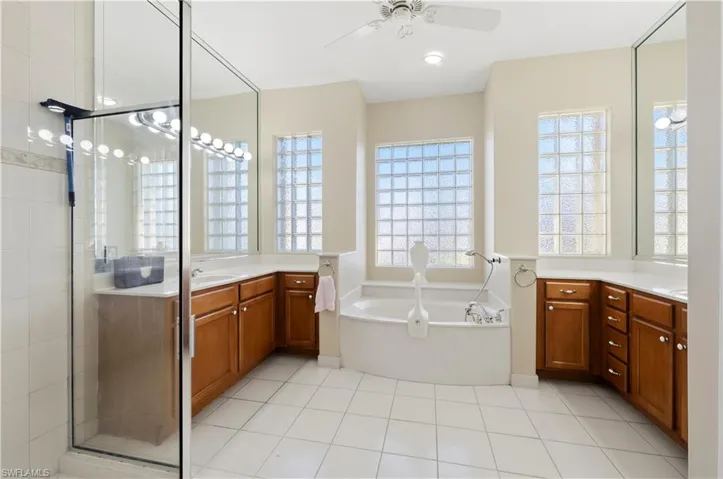 Full bath with a shower stall, a bath, vanity, ceiling fan, and light tile patterned floors