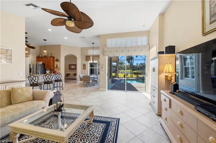 Living area with ceiling fan, a high ceiling, light tile patterned floors, arched walkways, and recessed lighting